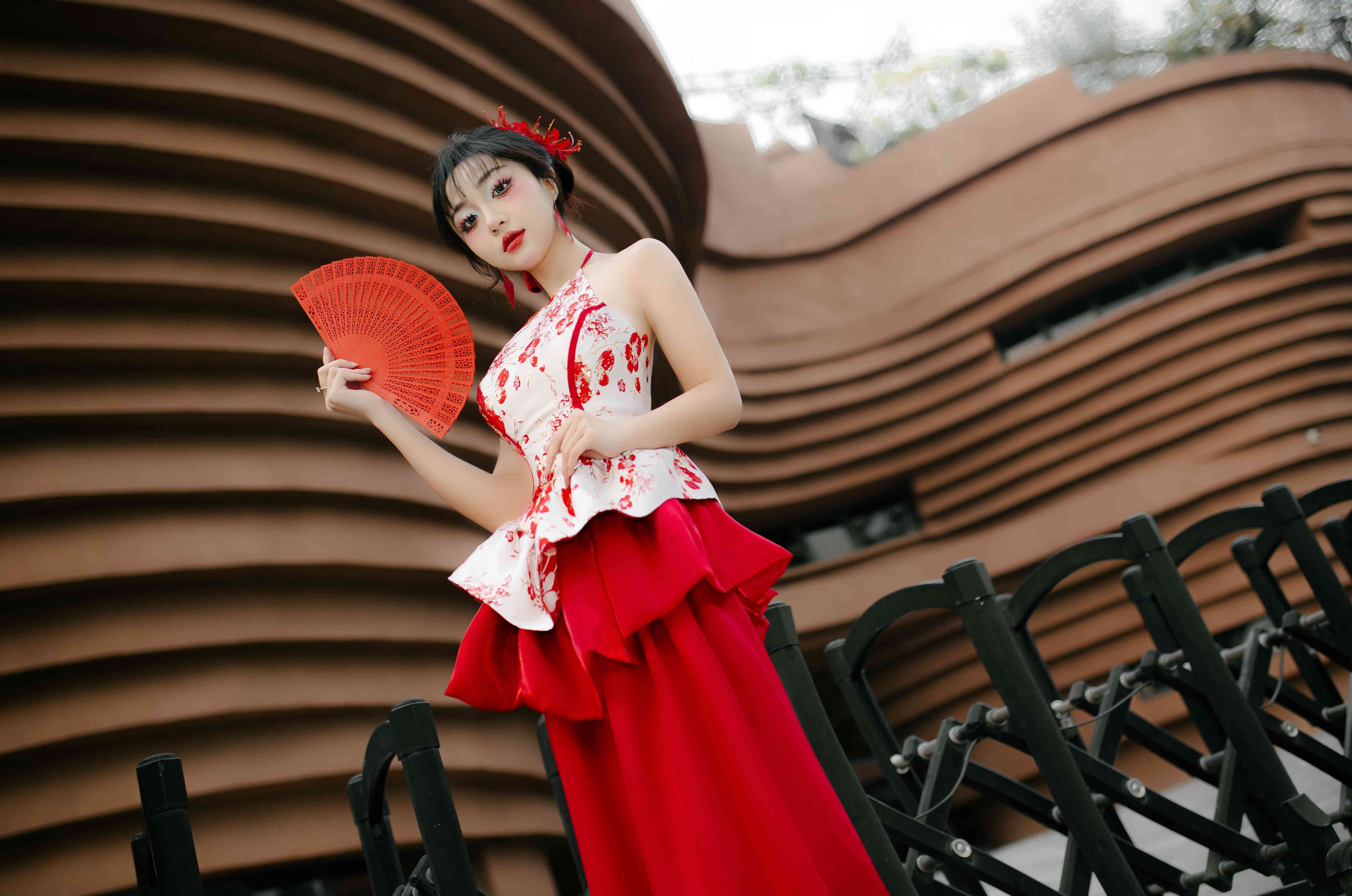 绿植与肌理建筑柔和虚化，端庄温婉神态，红白撞色国风裙层次饱满，尽显古典东方韵味